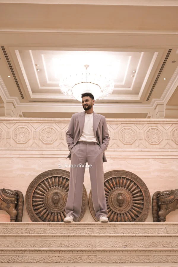 Classic Indian groom pose featuring the groom standing confidently in his embroidered wedding suit.
