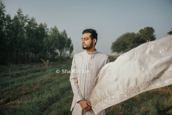 Modern Indian groom posing in a structured sherwani with a confident stance for an editorial wedding portrait.