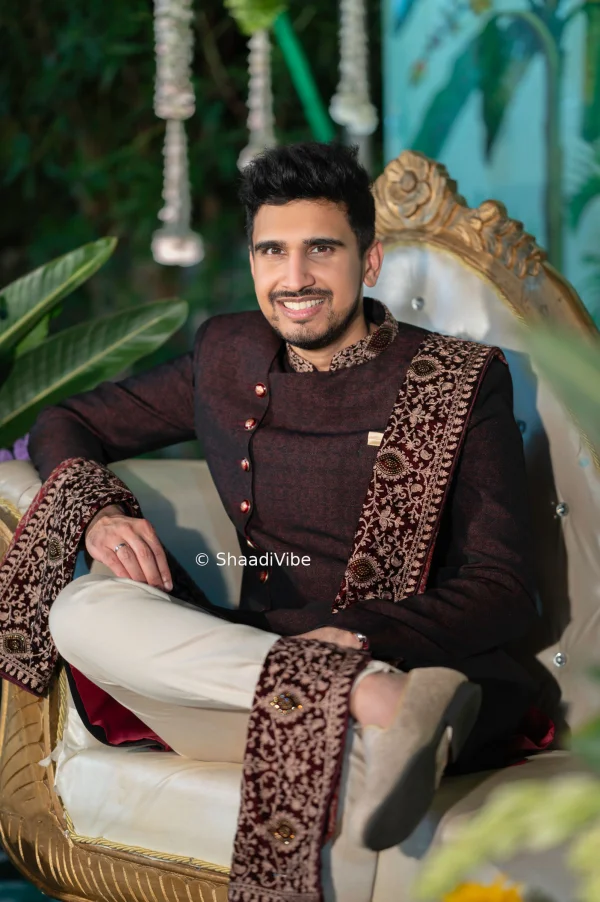 Timeless Indian groom portrait capturing the complete wedding look with a classic maroon indowestern with matching khesh pose and traditional styling.