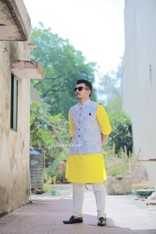 Timeless Indian groom portrait capturing the complete pre wedding look in grey bundi and yellow kurta with pants for his pre wedding festivities.