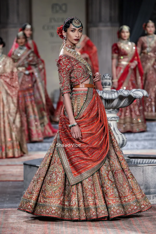 Luxury red bridal lehenga decorated with intricate gold embroidery for a grand and regal wedding appearance dupatta and belt.