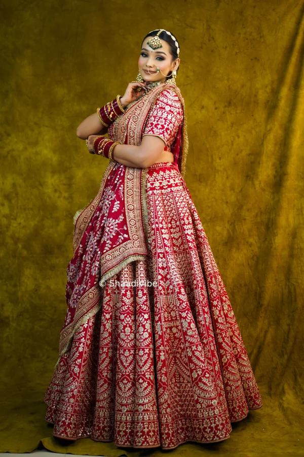 Luxury red bridal lehenga decorated with intricate gold embroidery for a grand and regal wedding appearance.