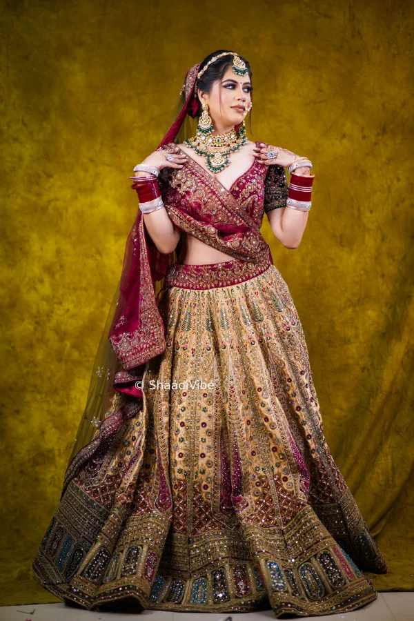 Gold bridal lehenga featuring detailed embellishment and a luxurious silhouette for a statement Indian wedding look with contrast maroon blouse and dupatta.