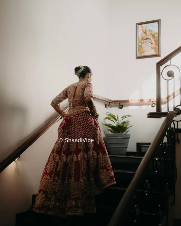Luxury red bridal lehenga decorated with intricate gold embroidery for a grand and regal wedding appearance.