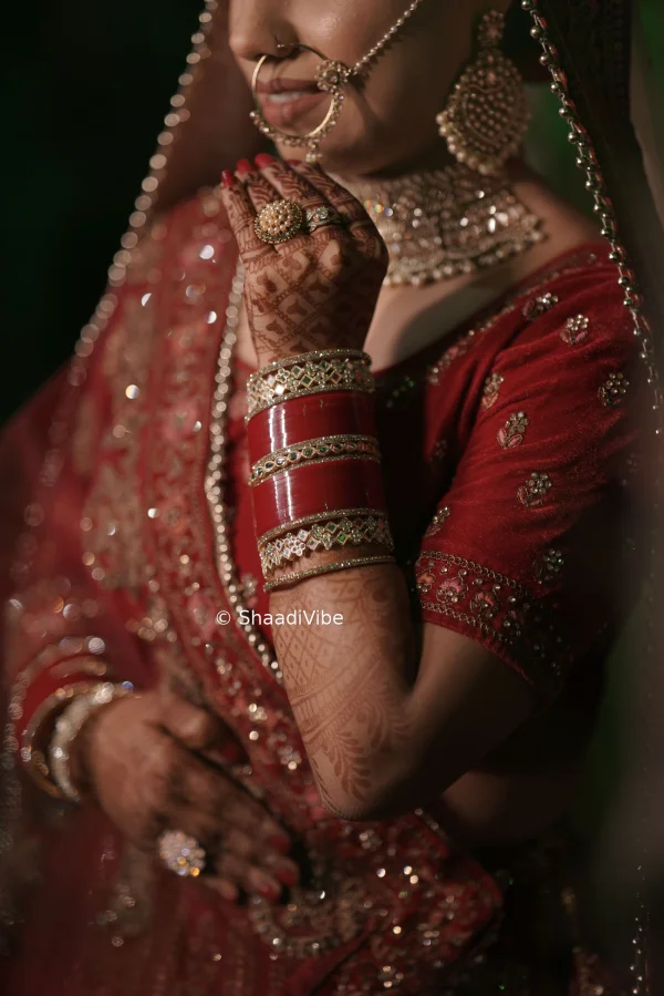 Traditional Indian bridal portrait highlighting the bride’s red lehenga, dupatta, jewellery and classic bridal styling.