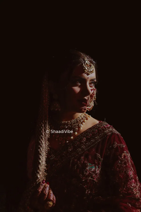 Soft natural-light bridal portrait capturing an Indian bride in an elegant wedding look against a minimal backdrop.