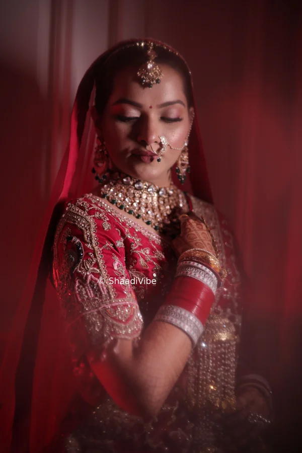 Elegant Indian bridal portrait featuring a bride in a traditional red lehenga with statement jewellery and soft bridal makeup.