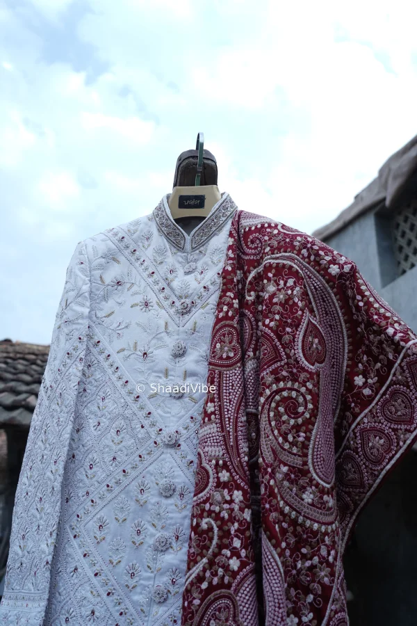 Elegant beige sherwani with subtle embroidery for a refined and understated wedding day look with contrast maroon dupatta.