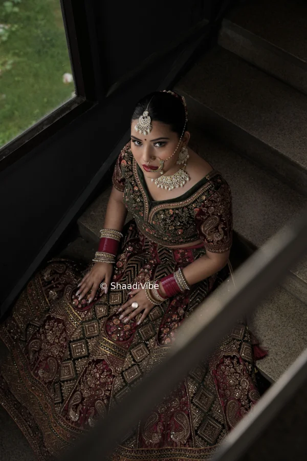 Traditional seated bridal pose with the bride resting gracefully beside her lehenga for a classic wedding photograph.
