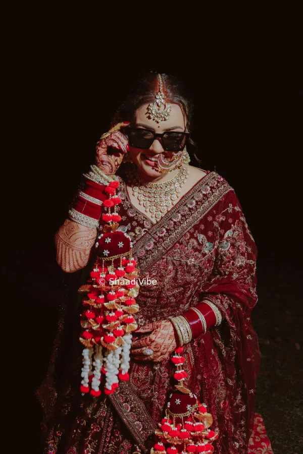 Confident Indian bride posing directly toward the camera with her hands gracefully arranged for a striking wedding photograph.