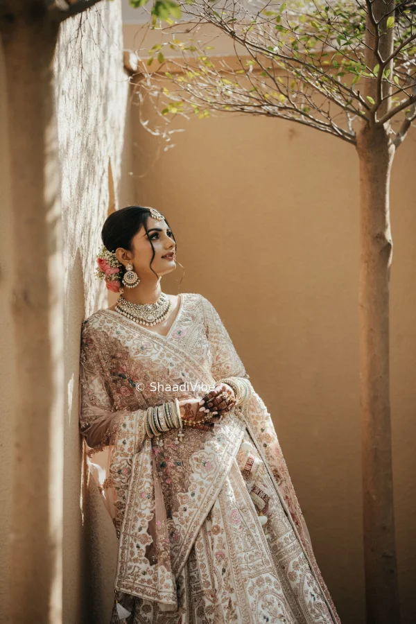 Indian bride creating a soft and romantic pose by gently holding her veil while looking away from the camera.