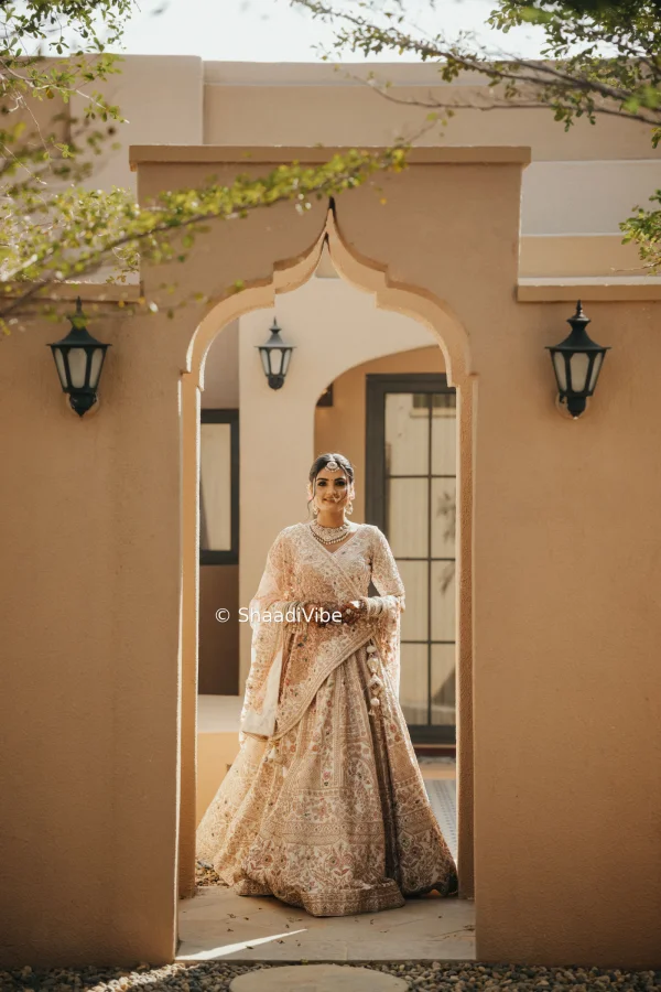 Natural bridal pose capturing the bride walking slowly while holding her dupatta and smiling during the wedding day.