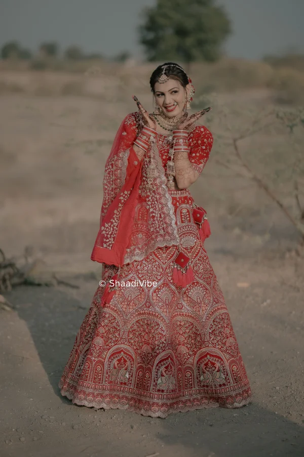 Confident Indian bride posing directly toward the camera with her hands gracefully arranged for a striking wedding photograph.