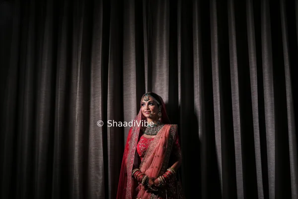 Romantic bridal pose featuring the bride looking down while gently holding the edge of her embroidered lehenga.