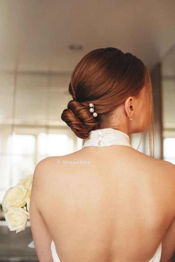 Romantic bridal hairstyle featuring a textured bun, soft curls and fresh flowers for a dreamy wedding day look.