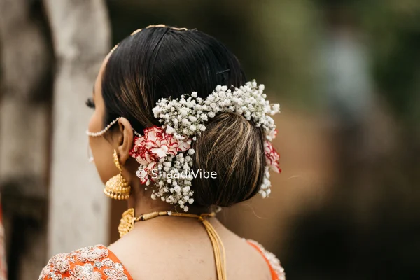 Romantic bridal hairstyle featuring a textured bun, soft curls and fresh flowers for a dreamy wedding day look.
