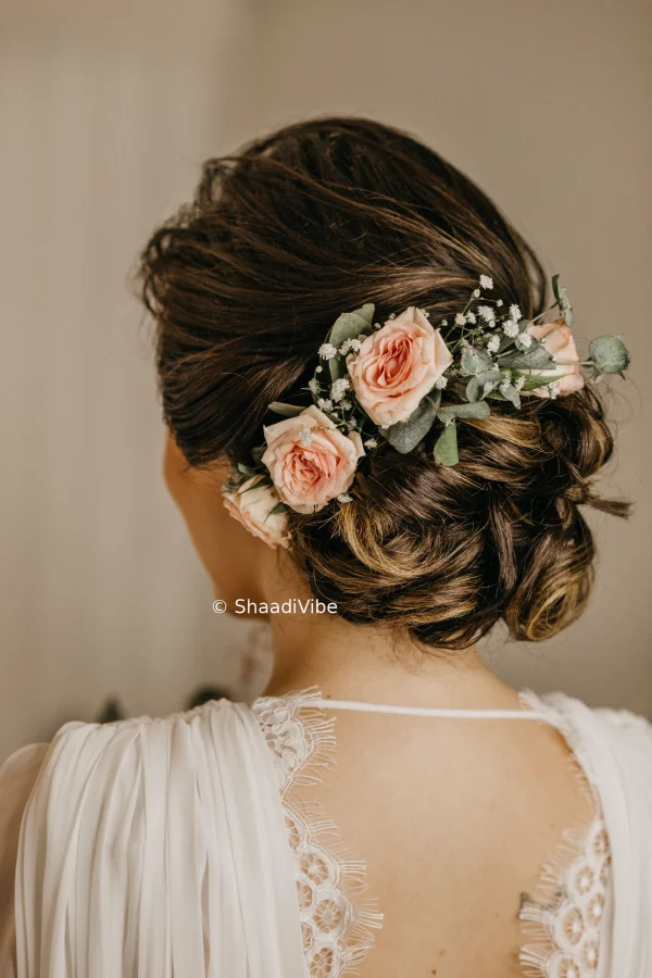 Traditional bridal bun hairstyle adorned with white flowers and delicate hair accessories for a sophisticated Indian wedding look.