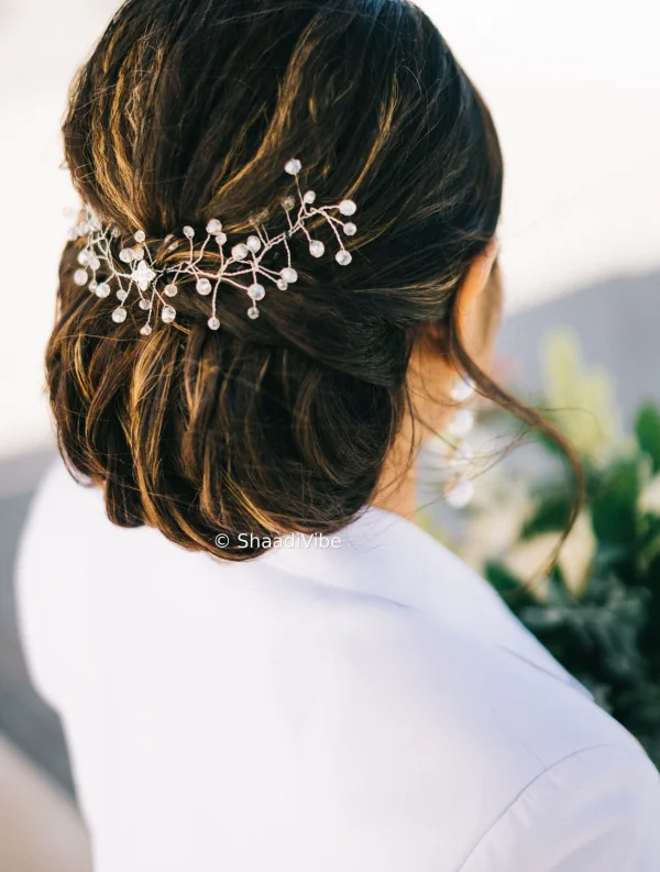 Classic low bridal bun paired with delicate hair jewellery for an elegant and refined Indian bridal look.