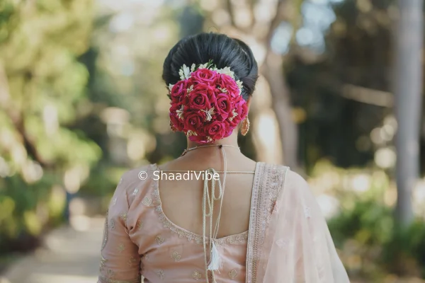 Elegant Indian bridal bun decorated with fresh flowers, creating a classic and timeless wedding hairstyle.